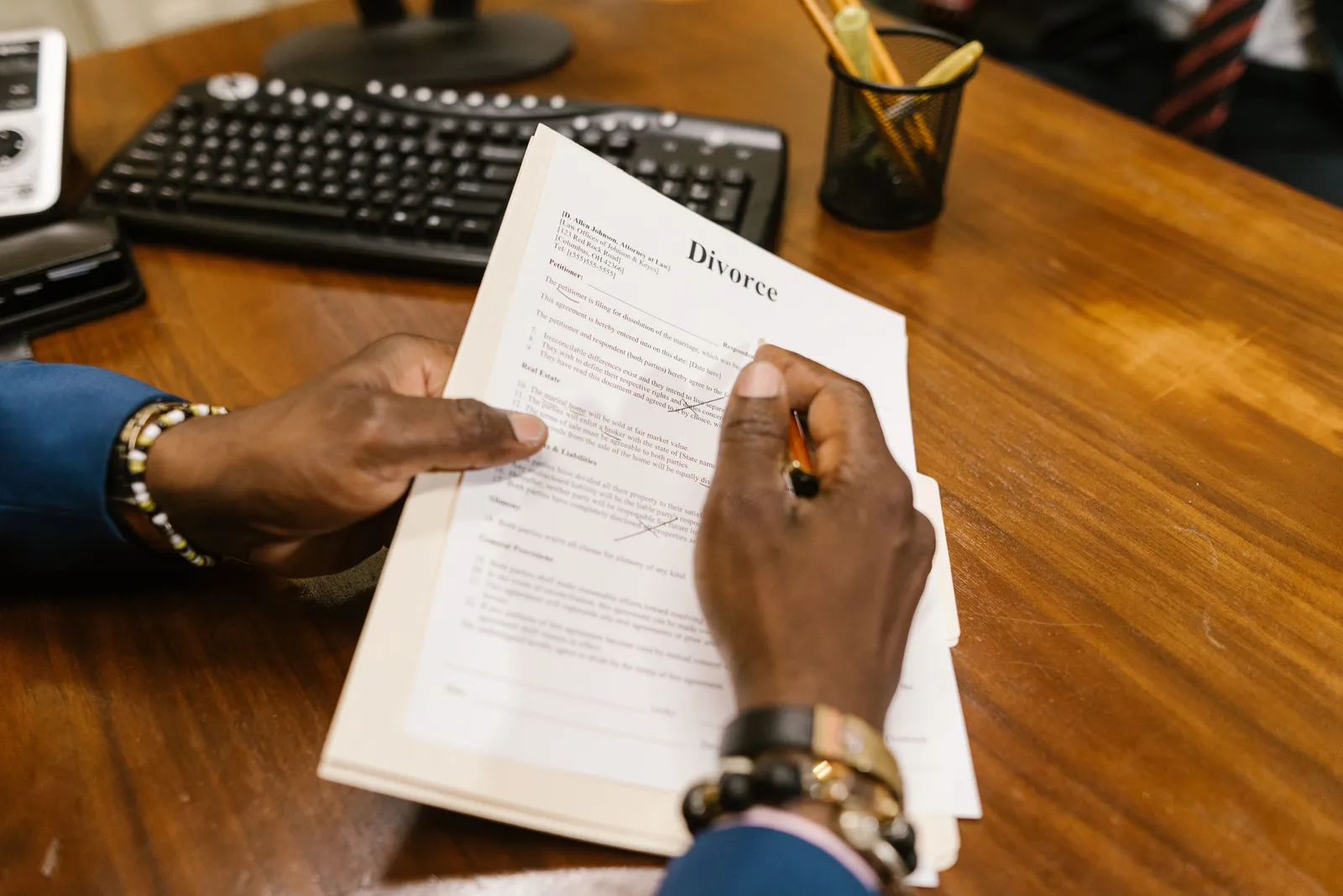 A person signs official divorce documents at an office desk