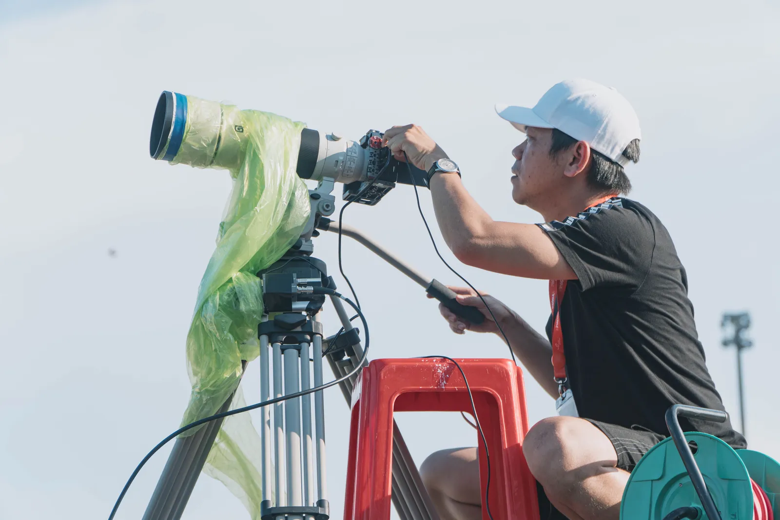 Man using a telephoto lens and tripod outdoors with a white sky backdrop