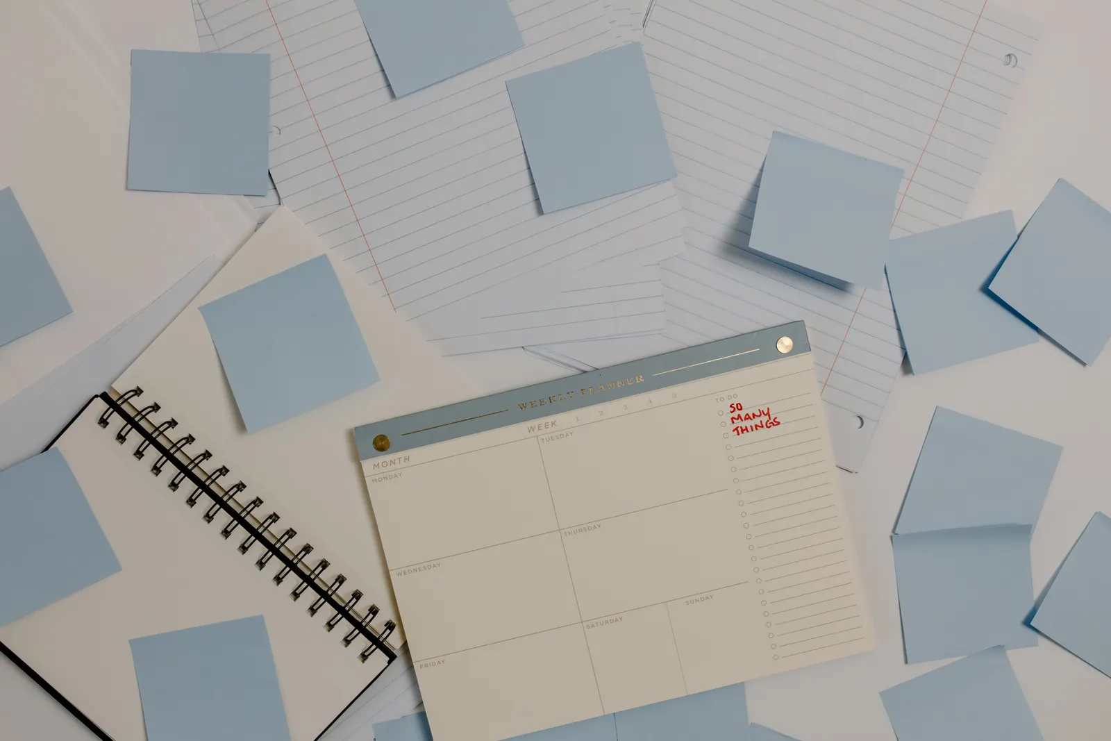 Top view of a desk with planner, sticky notes, and lined papers for organization