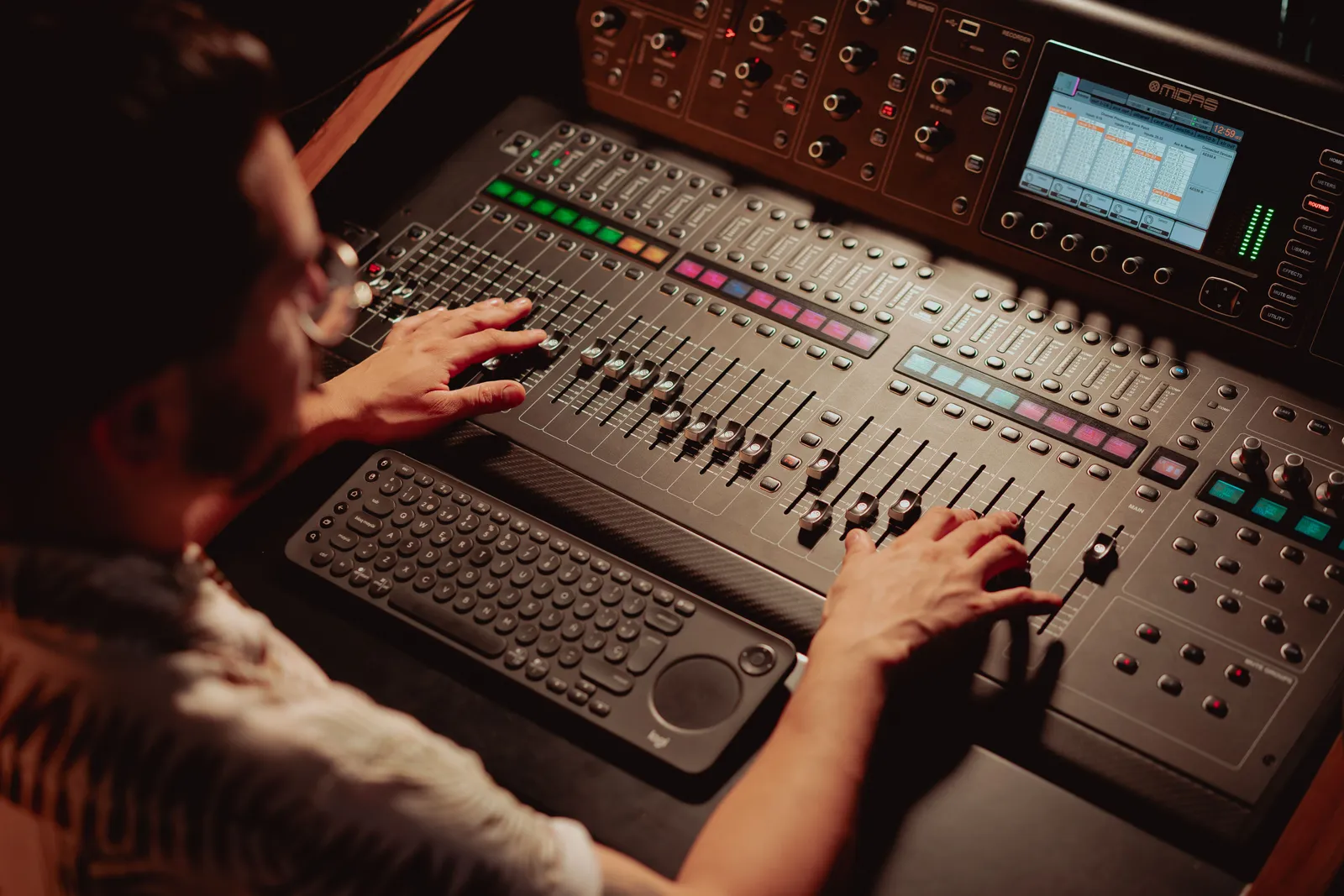 Audio engineer using mixing console in recording studio, adjusting sound levels