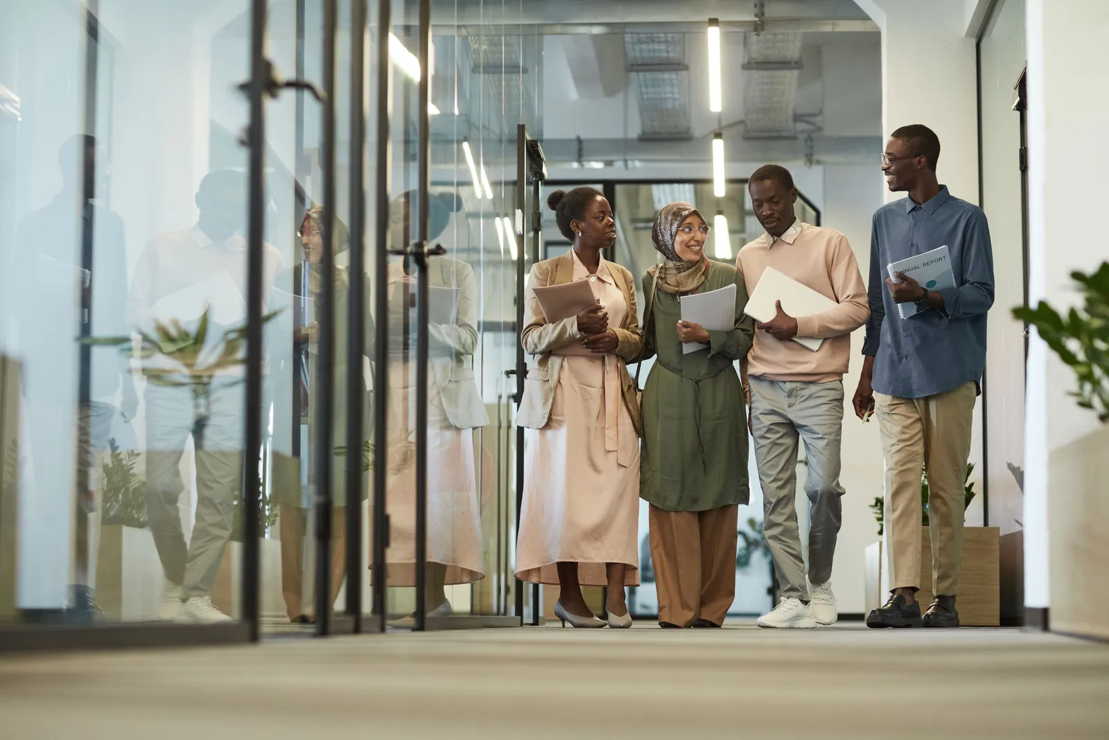 A diverse group of colleagues walking through a modern office hallway, engaged in conversation