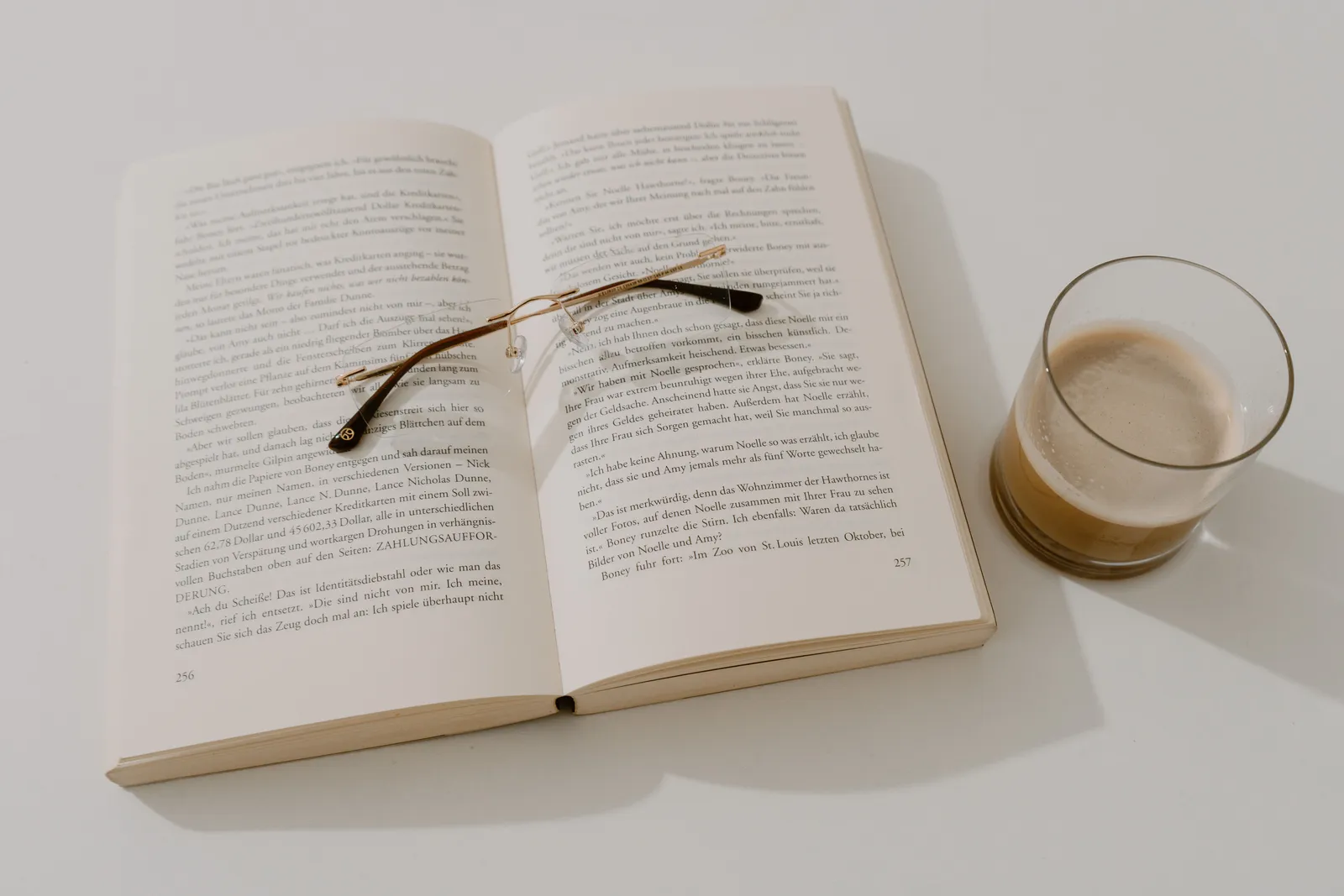 Open book with reading glasses and coffee on a white table, creating a serene reading corner