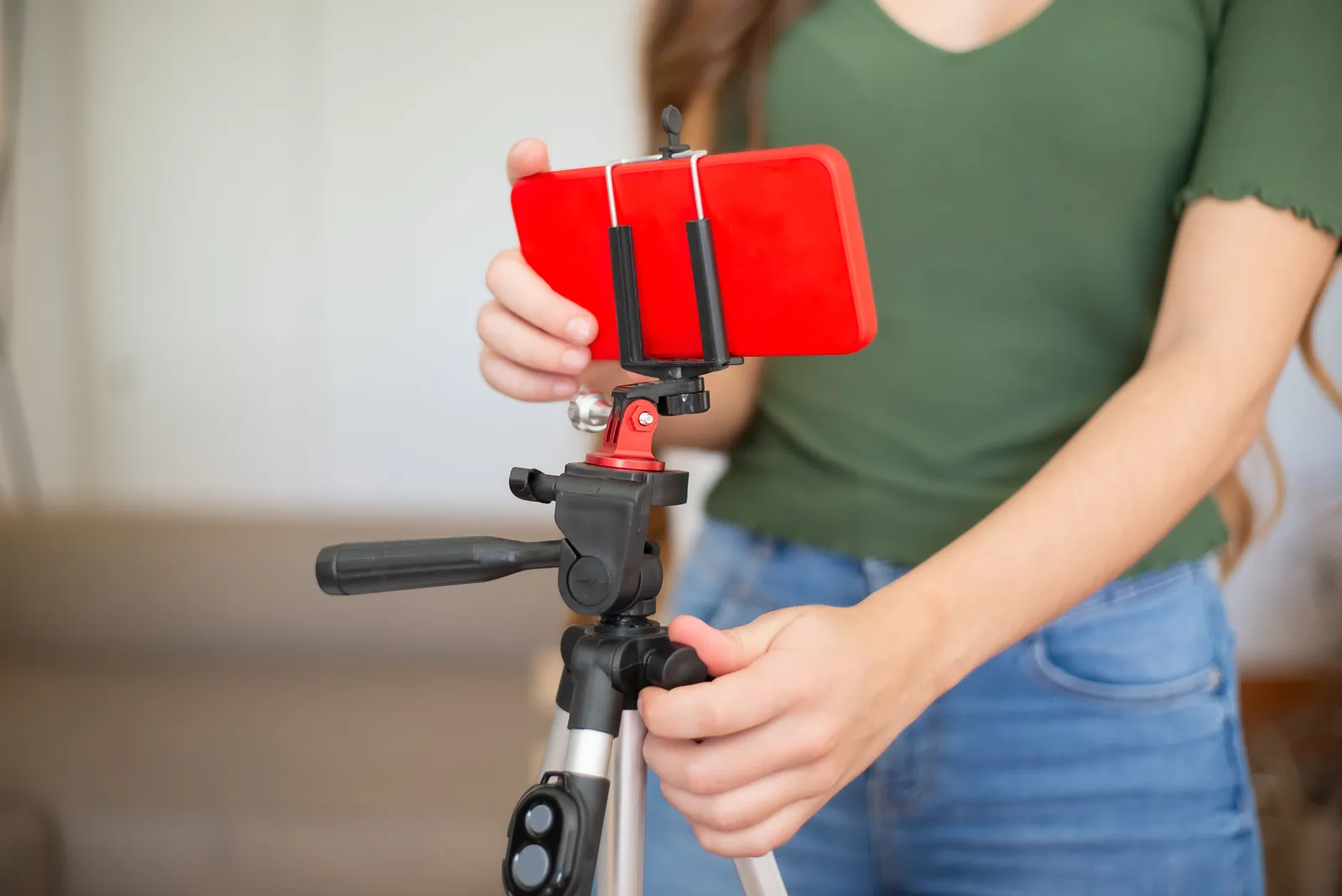 Female adjusting smartphone onto tripod for recording indoors