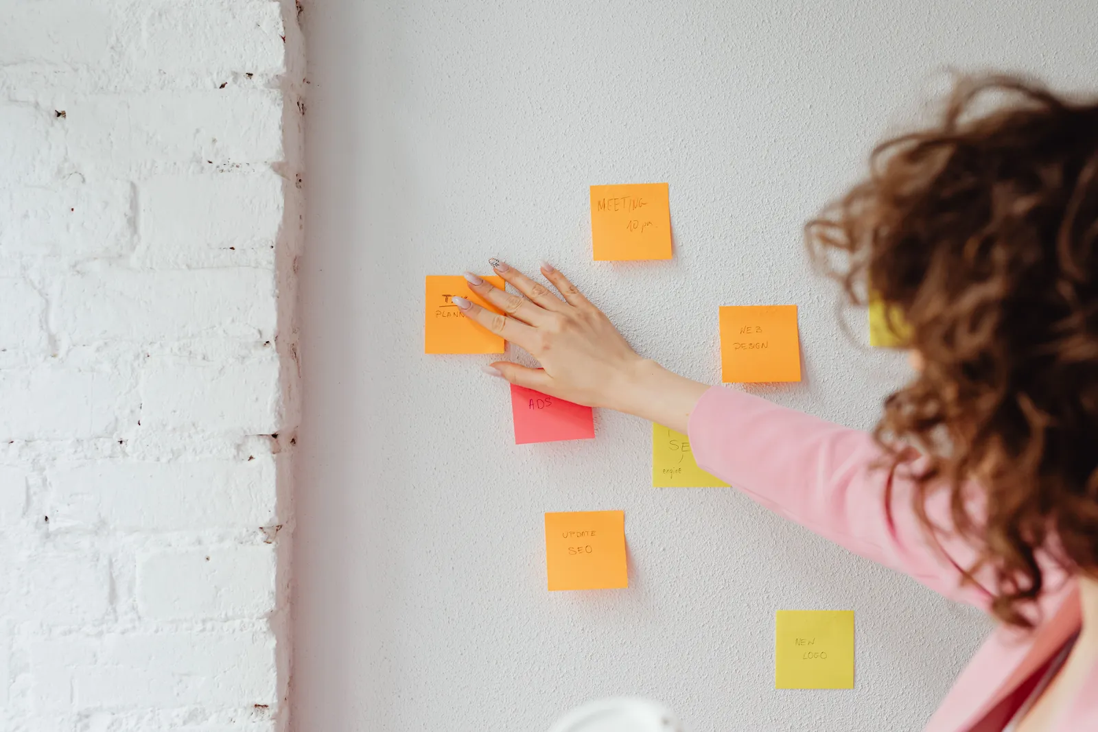 A woman planning ideas with colorful sticky notes on a wall. Ideal for conceptual and organizational themes