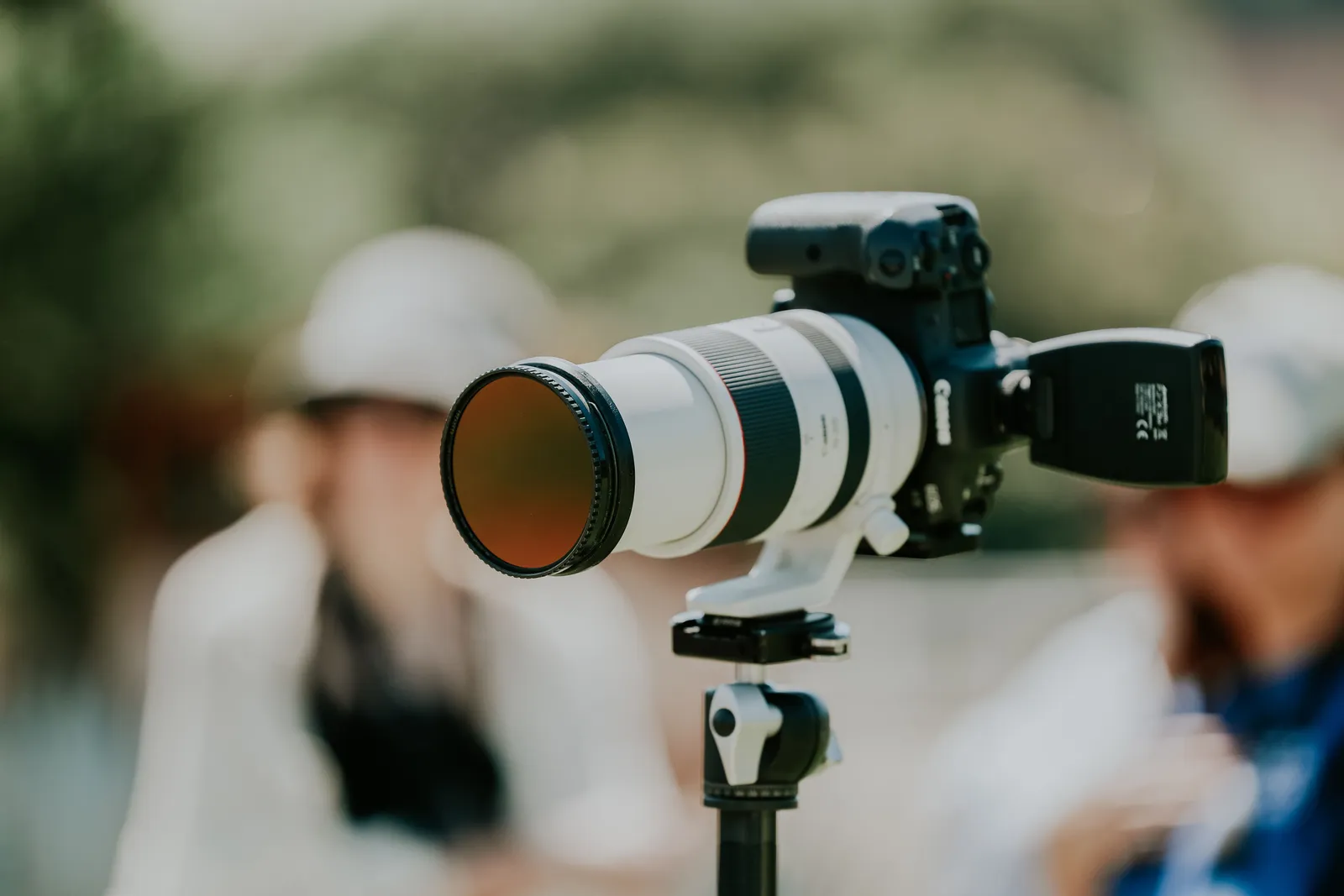 Professional camera with telephoto lens on tripod, blurred outdoor background, showing focus and precision