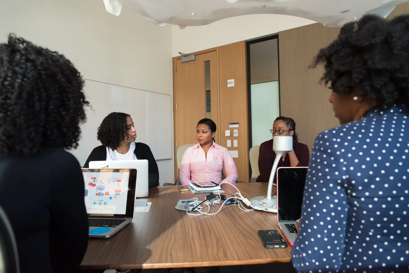 Diverse team of adults collaborating in a meeting room with laptops and documents on the table