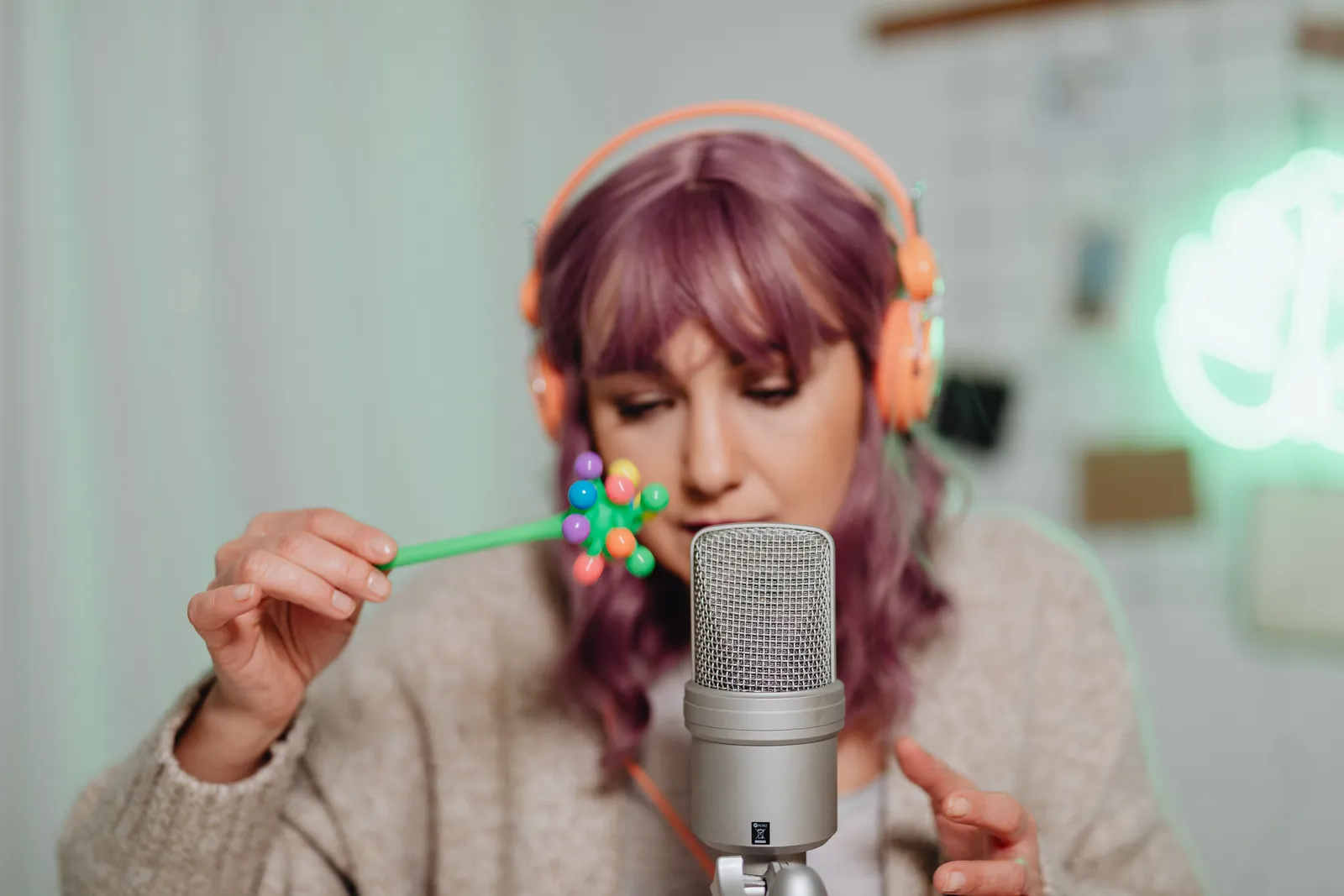 Woman with purple hair recording ASMR using a microphone and colorful props
