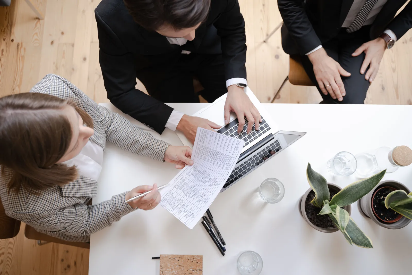 Overhead view of colleagues collaborating at a desk with laptop and documents in a business meeting