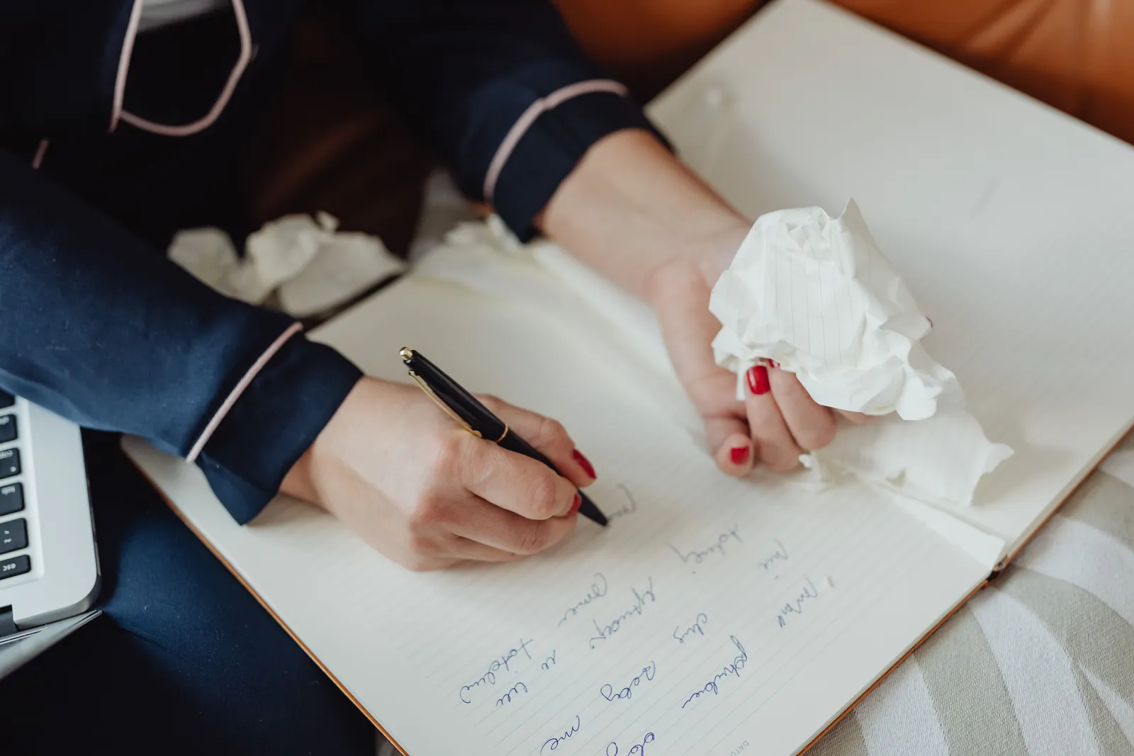 Hands writing in a notebook with crumpled paper, focus on creativity and ideas