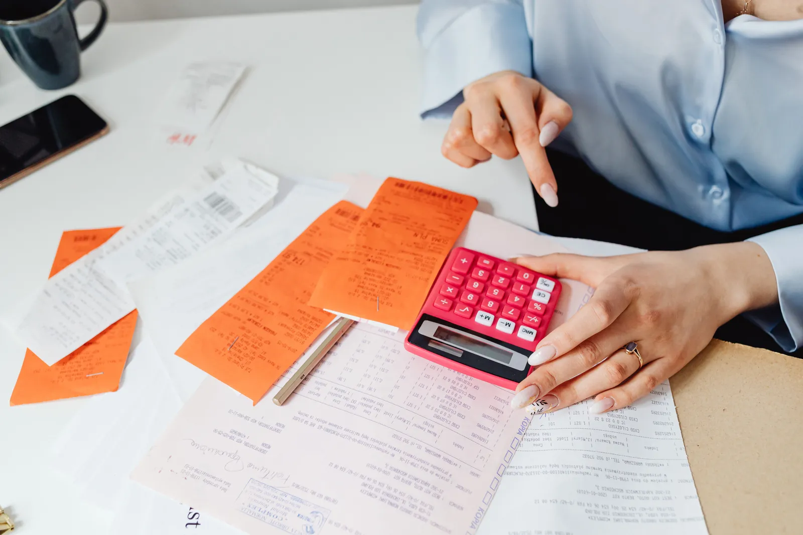 Businesswoman calculates expenses using receipts and calculator at desk. Ideal for finance, accounting themes