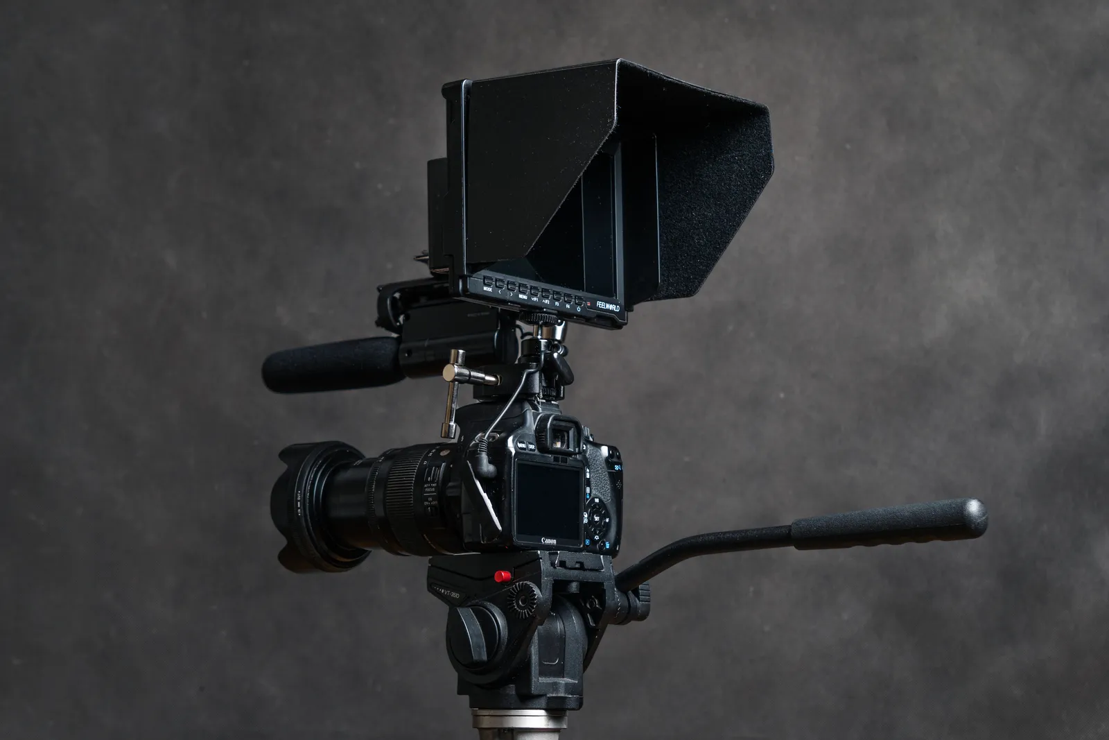 Studio shot of a DSLR camera with an attached lens and external monitor, ideal for videography