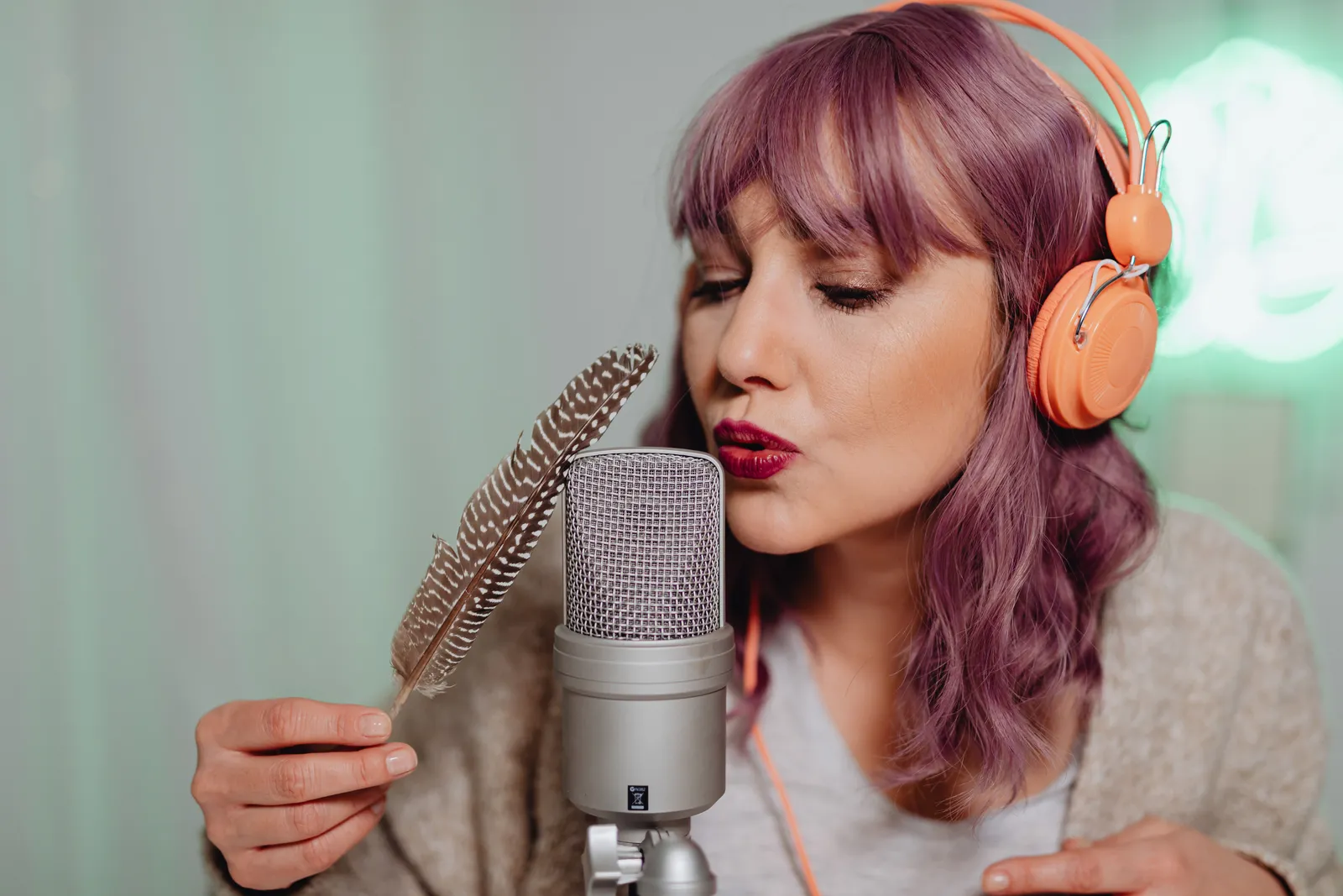 Woman using a feather to create ASMR sounds with a microphone indoors