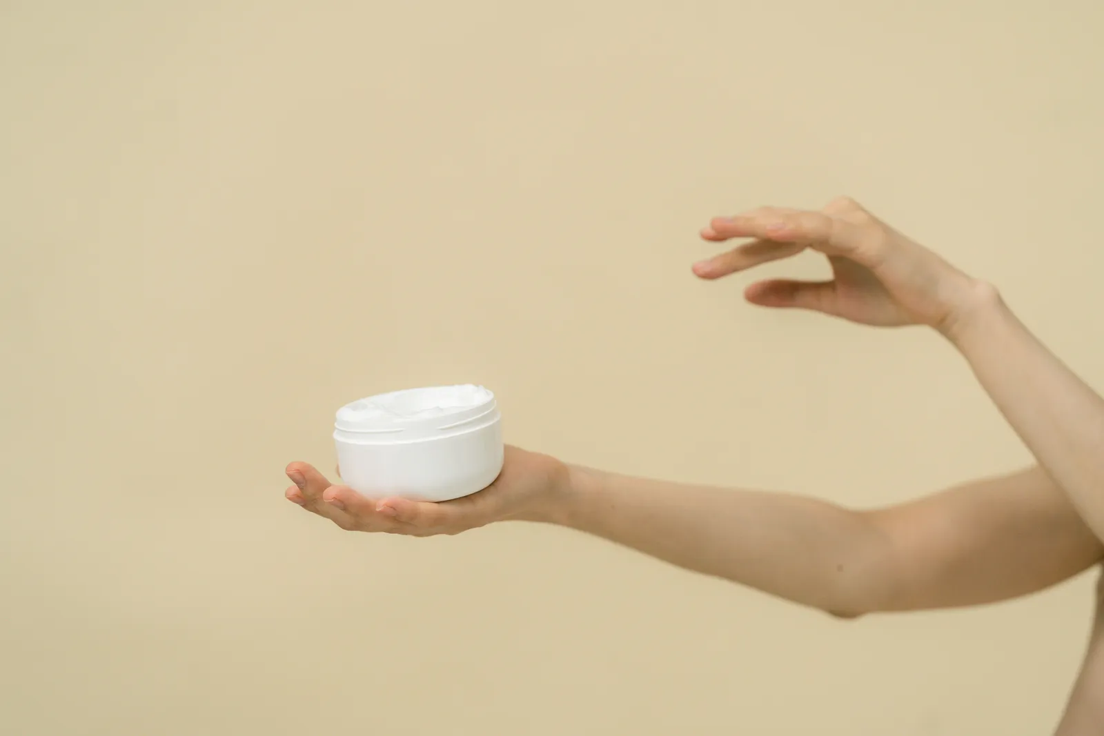Minimalist image of hands holding a cosmetic jar, emphasizing skincare and beauty