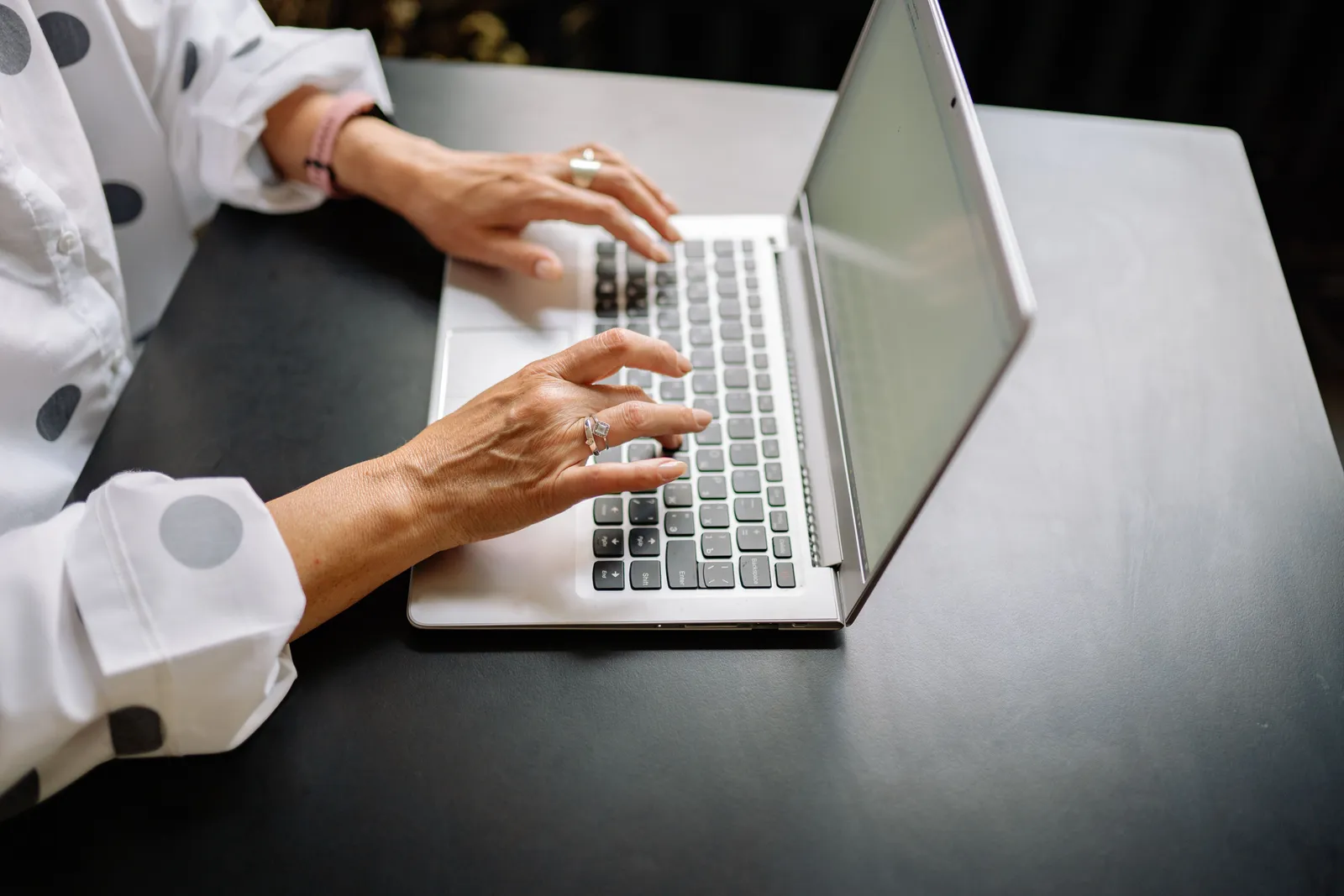 Close-up of a woman's hands typing on a laptop in a professional setting