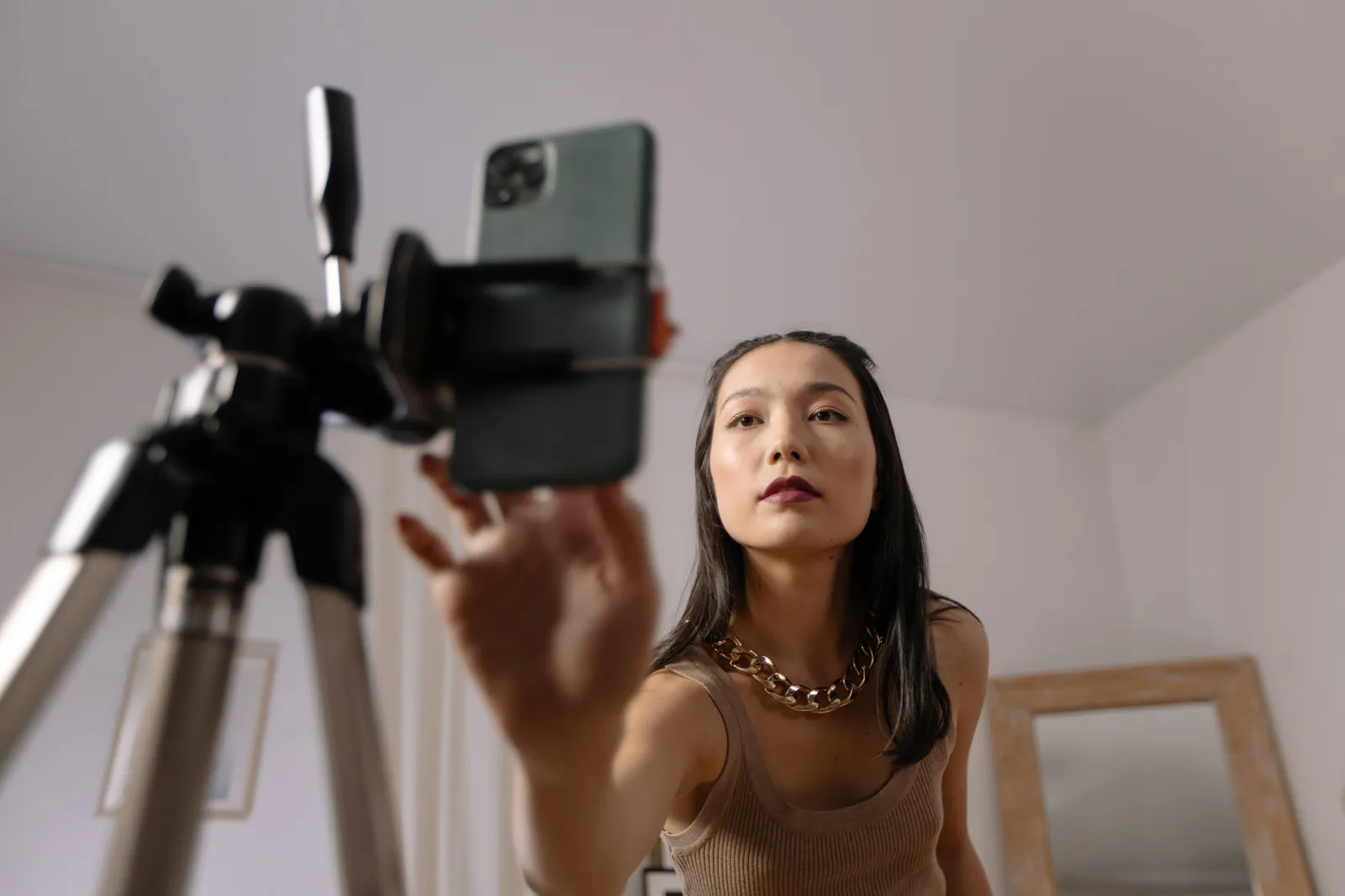 Woman setting up a smartphone on a tripod for vlogging indoors