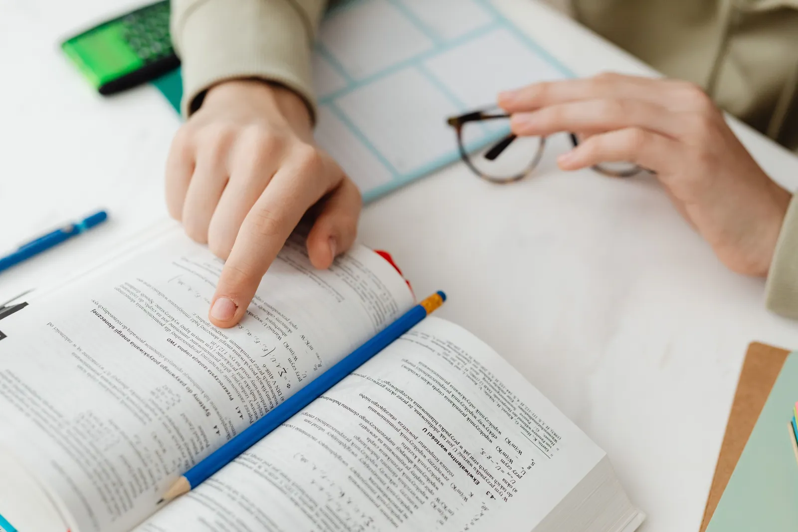 Close-up of a student studying math using a textbook and pencil at a desk indoors