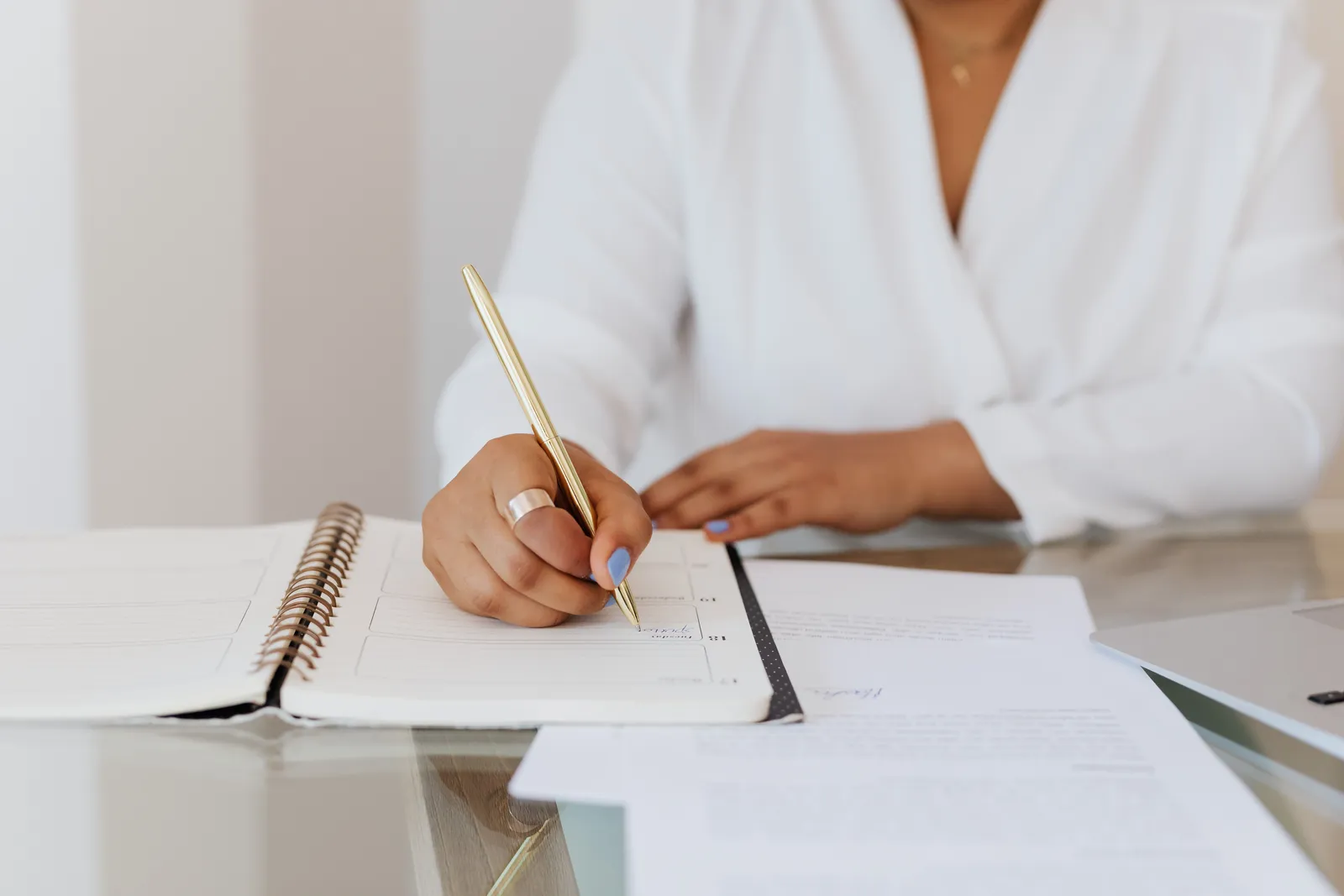 Close-up of a person writing notes in a planner with a gold pen, emphasizing organization
