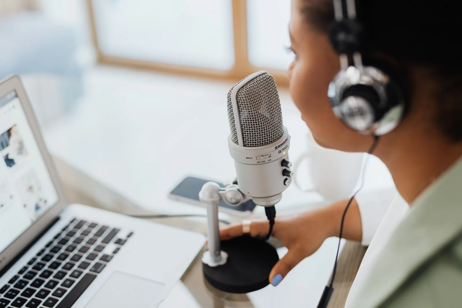 Professional woman recording a podcast or broadcast using a microphone and laptop at a desk