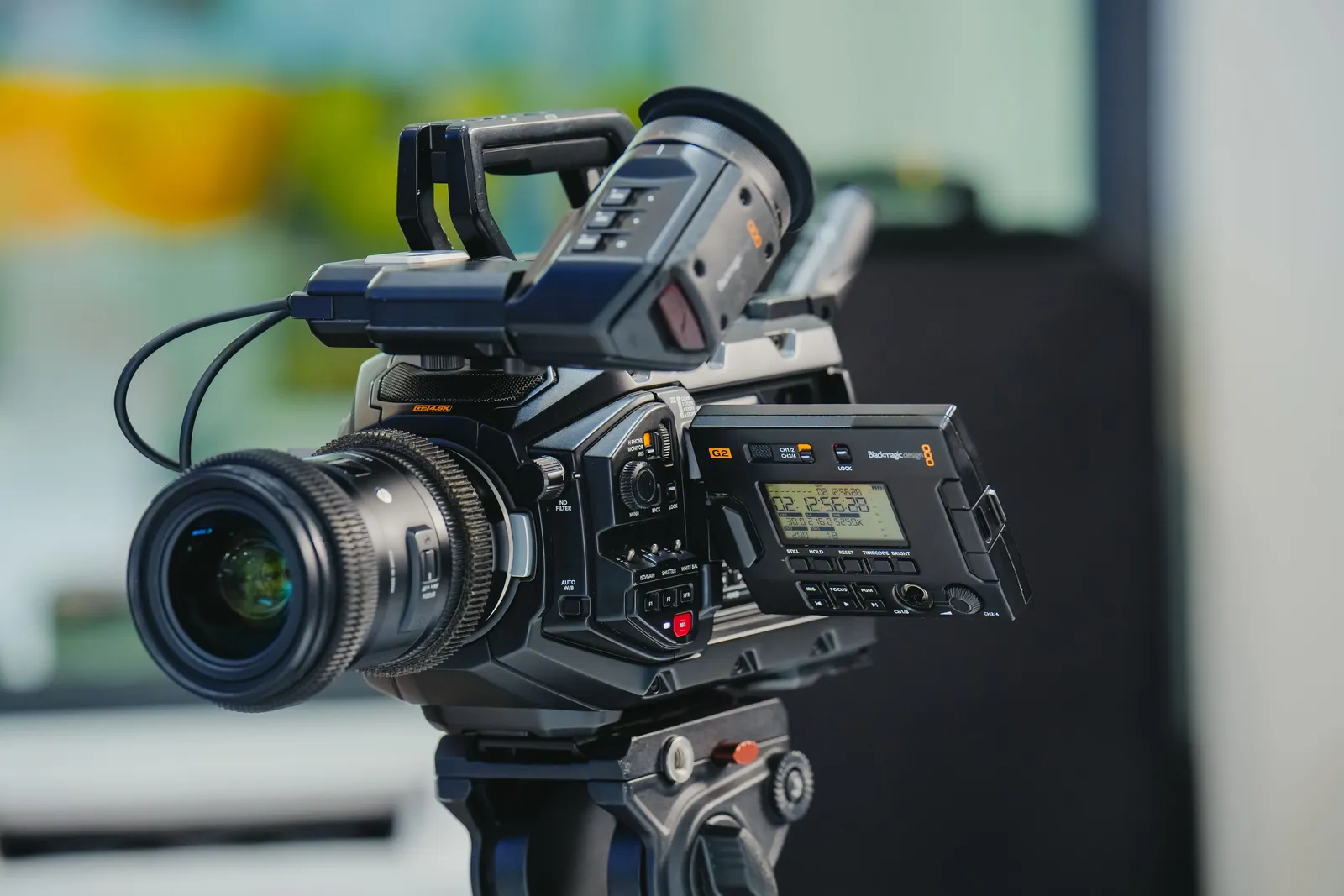 Close-up of a high-end video camera with attached lens on a sturdy tripod, ready for filming