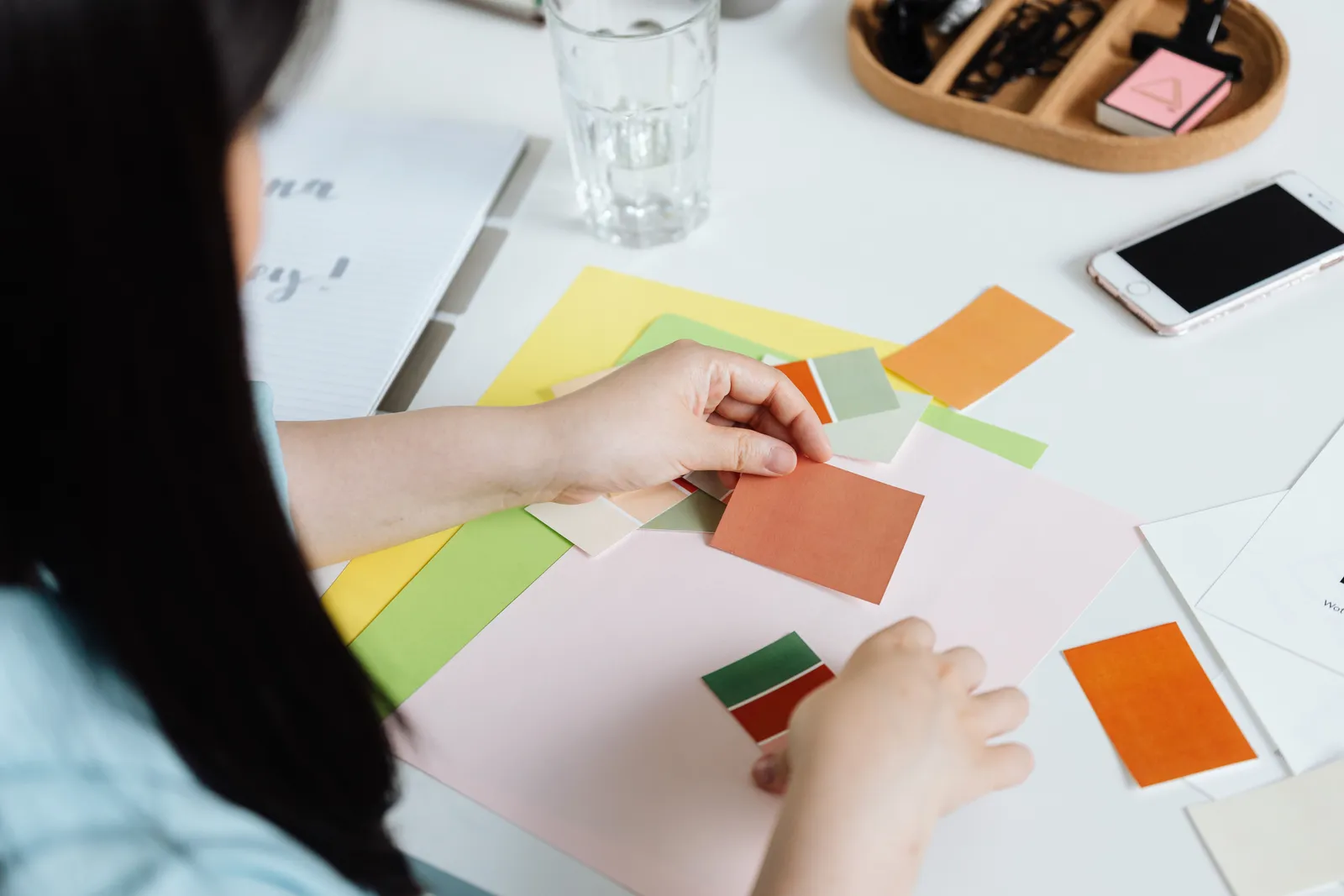 An interior designer arranging color swatches on a desk with a smartphone nearby
