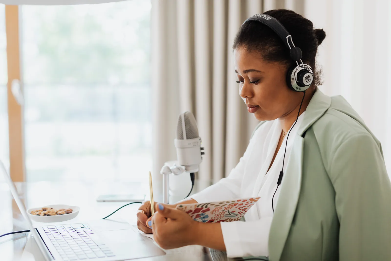 A focused woman recording a podcast indoors with headphones and microphone