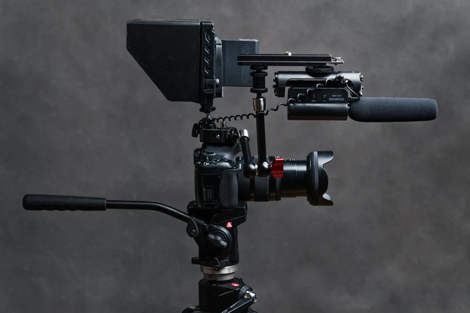 Close-up studio shot of a DSLR camera with video accessories including a microphone and tripod