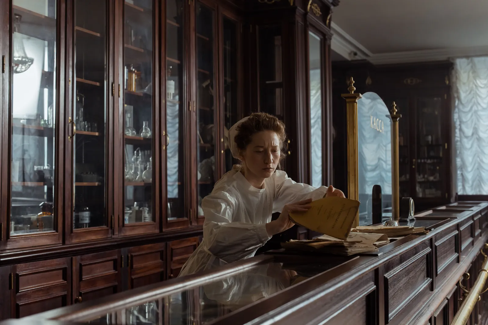 A woman in a retro pharmacy setting, organizing papers at the counter