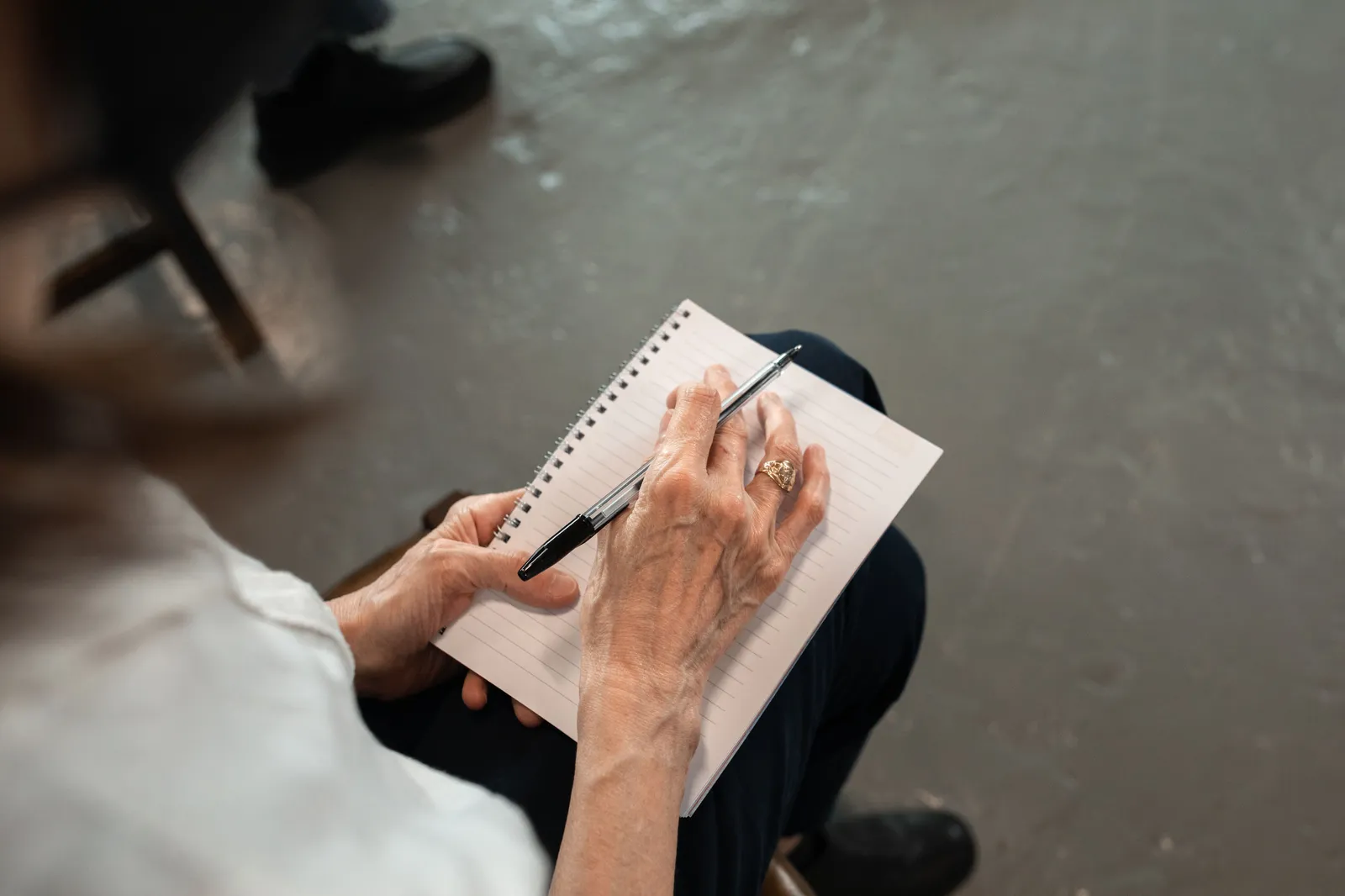 Close-up of senior hands with pen writing in a spiral notebook. Personal notes concept