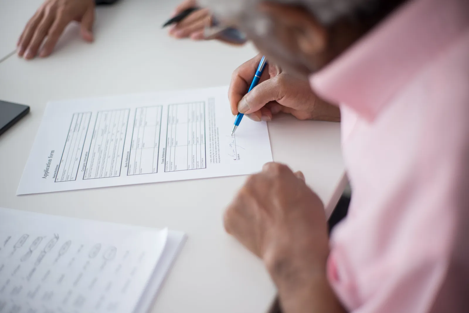 Elderly man signing important business document at desk in office setting