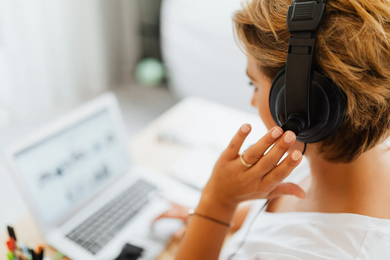 Woman at home using headphones and laptop for online work or video call