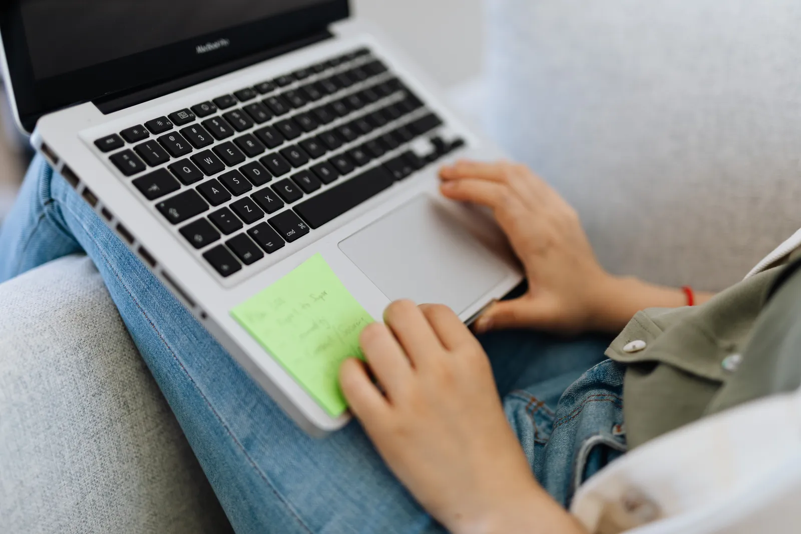 Close-up of a person using a laptop on a couch, focusing on relaxed working or studying