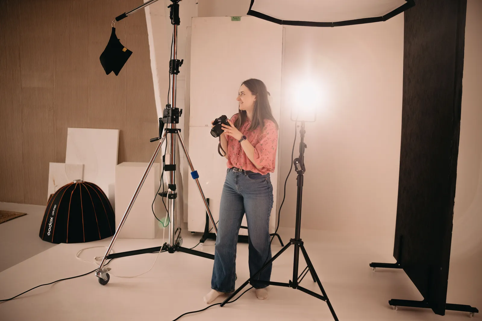 A woman holding a camera during a photoshoot in a well-equipped photo studio