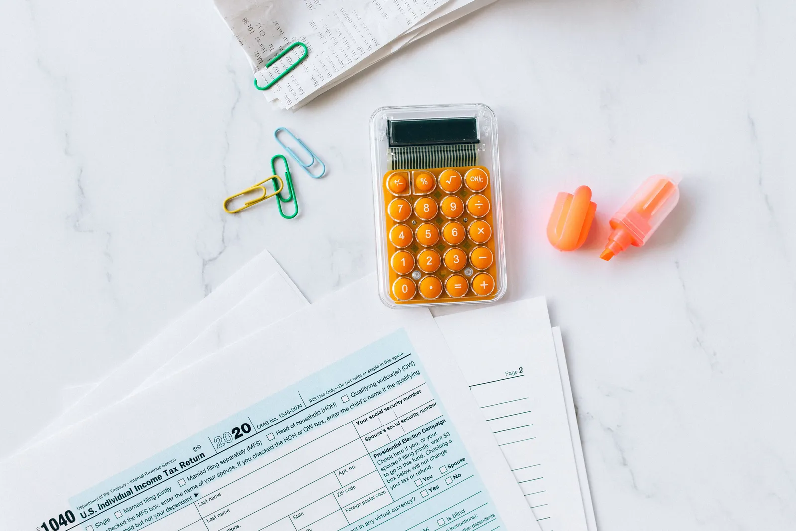 A flat lay image of tax forms, calculator, and office supplies on a desk