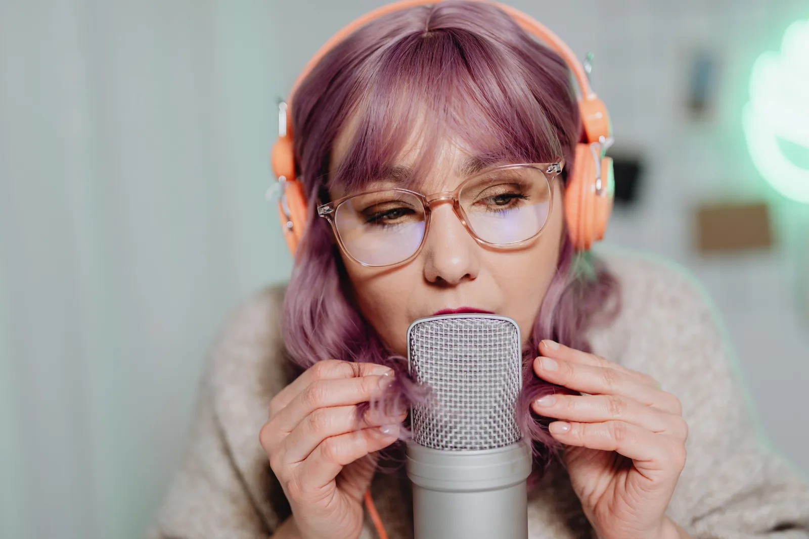 Close-up of a woman podcaster speaking into a microphone in a studio setting