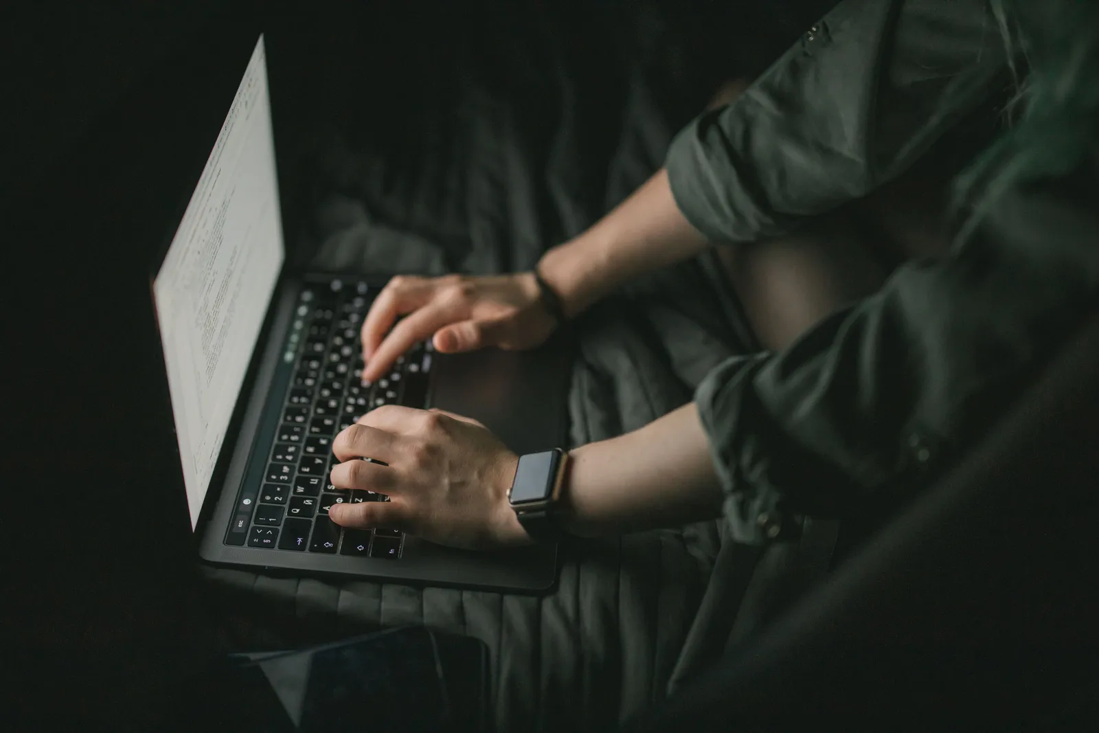 Hands typing on a laptop in a dark setting, technology and focus concept