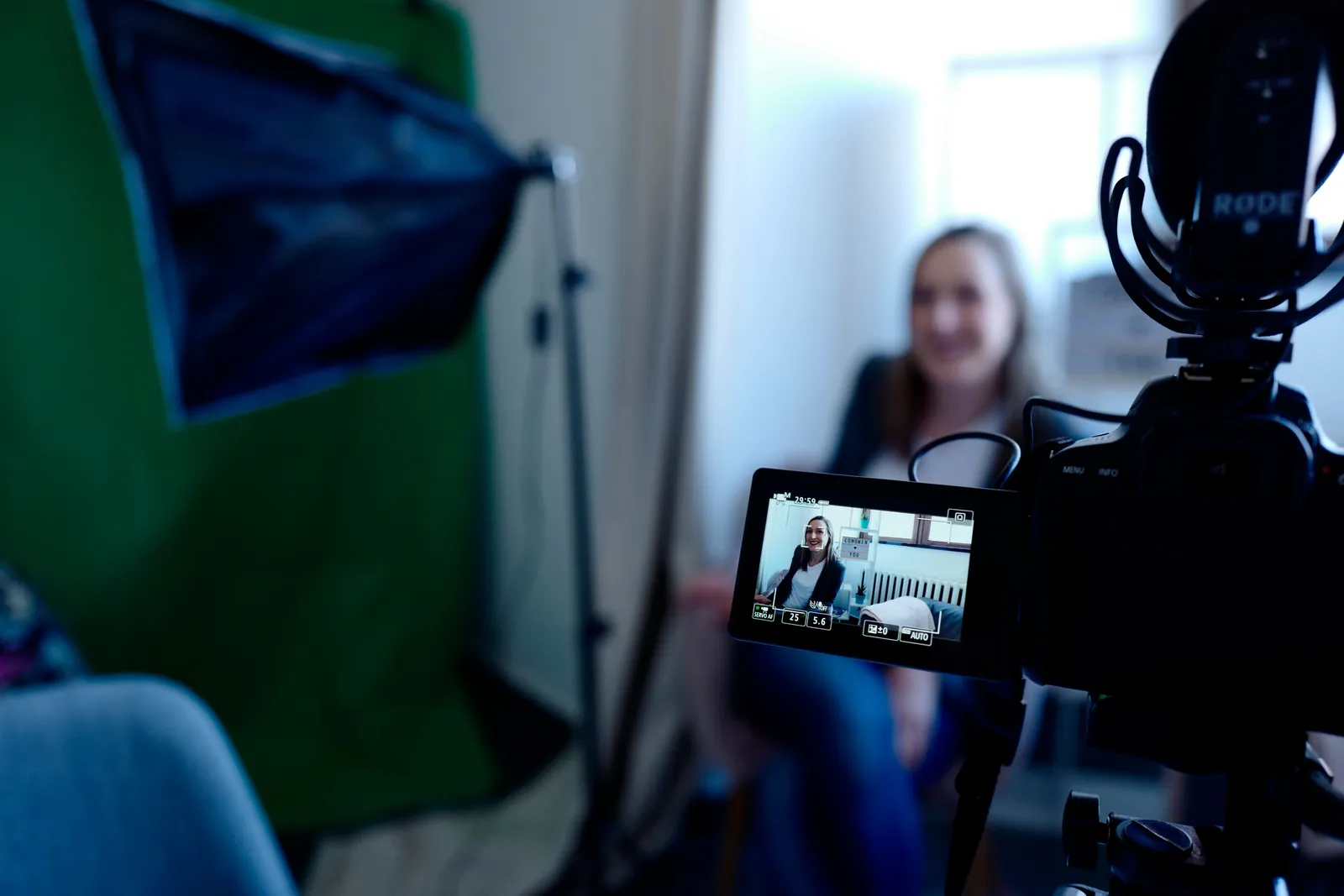Woman being recorded in a professional studio setup, using video camera and lighting equipment