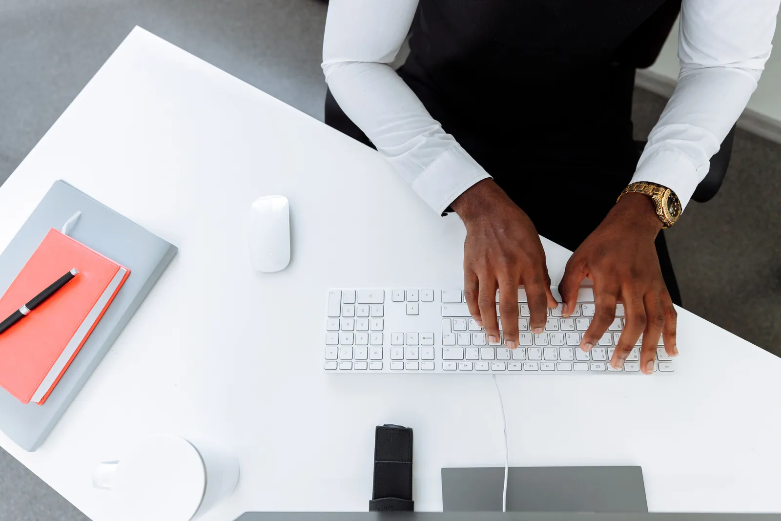 Business professional typing at a stylish desk with a modern keyboard and accessories