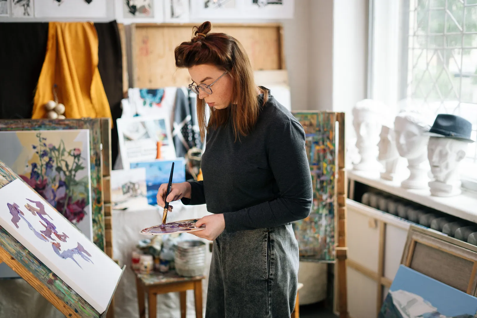 Woman artist painting on canvas in a bright, sunlit studio. Creative and focused atmosphere