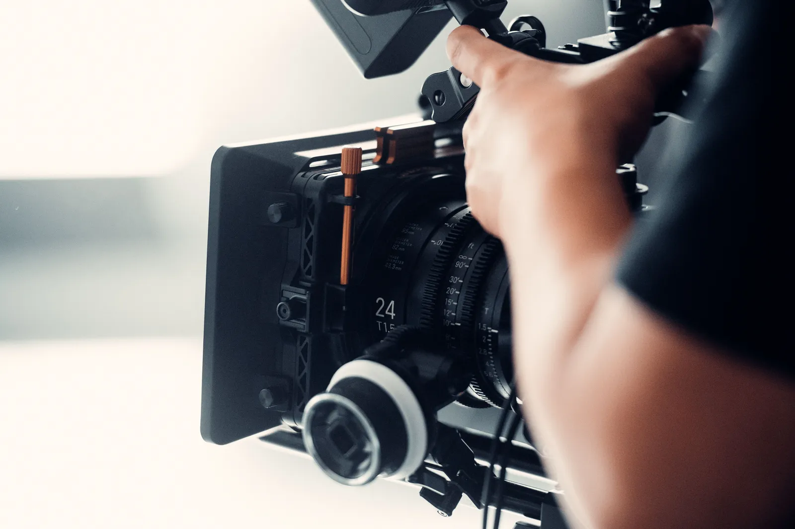 A professional video camera being operated by a person during filming indoors