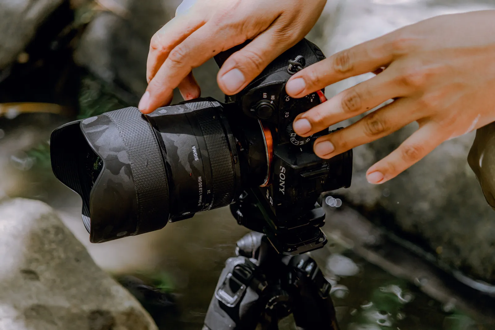 Hands close-up adjusting a camera on a tripod for outdoor photography