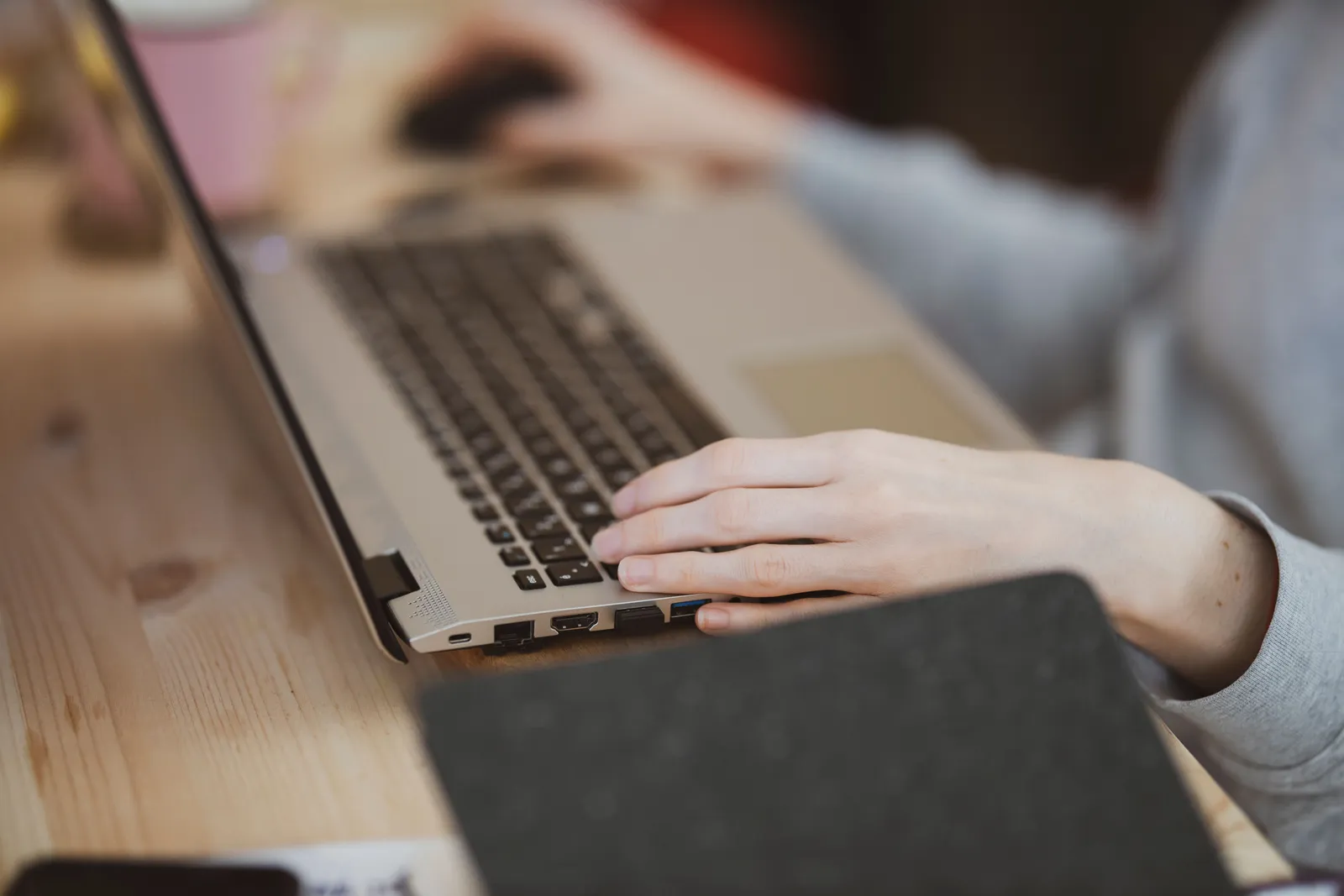Close-up view of a person typing on a laptop with focus on the hand and keyboard