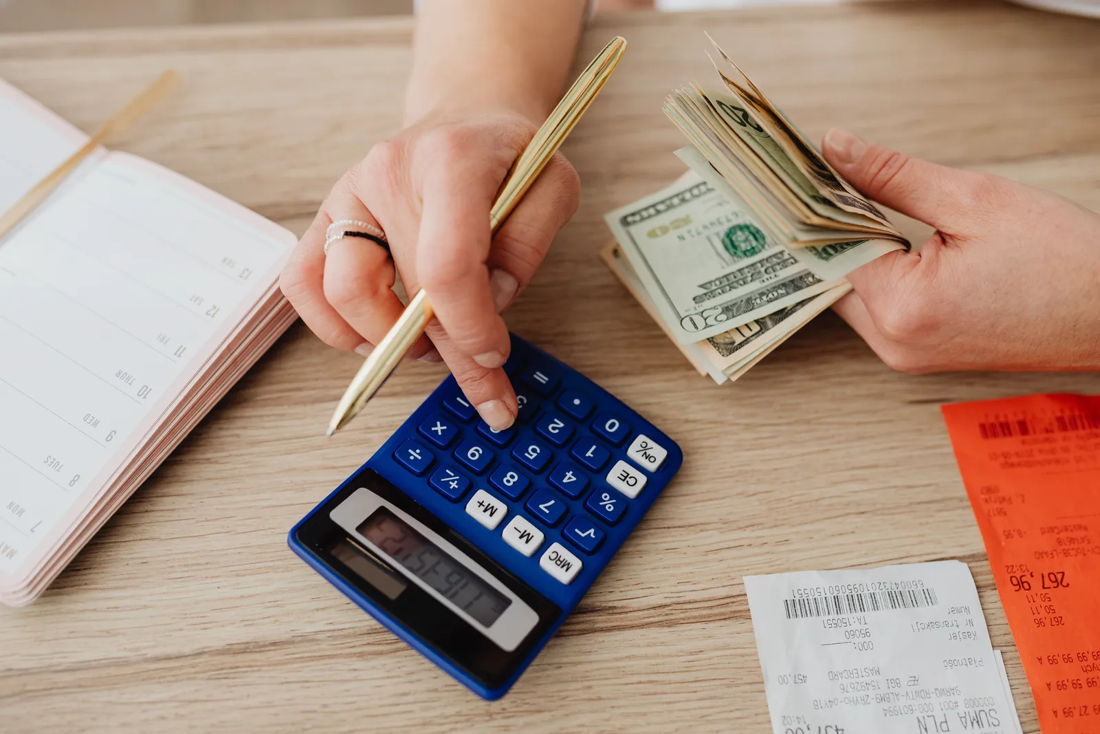 Hands handling cash and calculator for budget planning. Modern financial scene