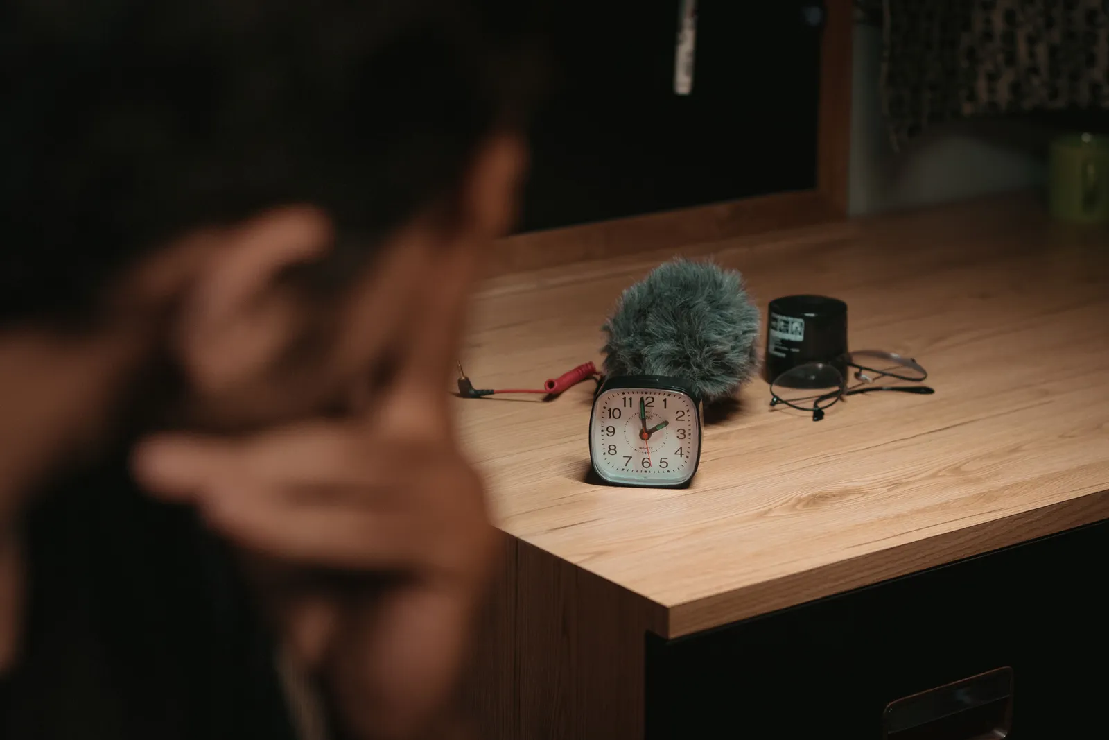 Wooden desk with a clock, wind muff, and recording gear, captured indoors