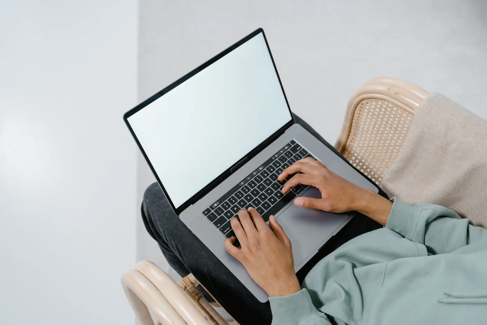 Overhead view of a person typing on a laptop in a comfortable armchair indoors