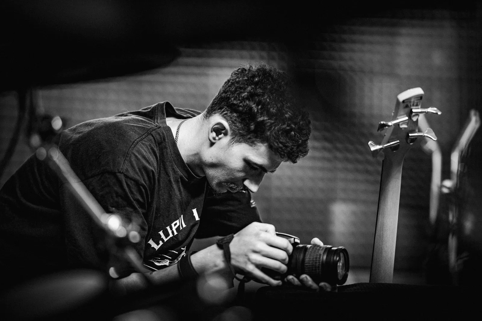 Black and white photo of a young man adjusting a camera in a music studio setting