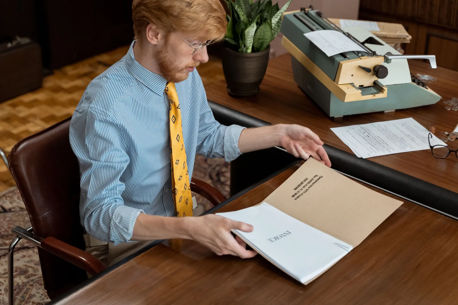 Man reviewing documents at vintage office desk with typewriter. Classic workplace setting