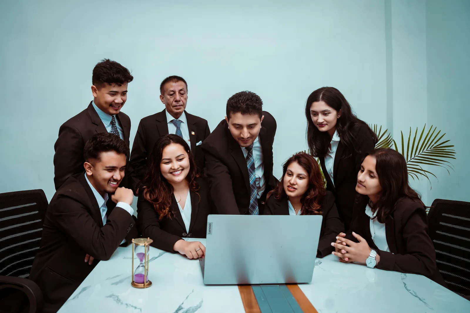 A diverse team of professionals collaborating around a laptop in a modern office setting