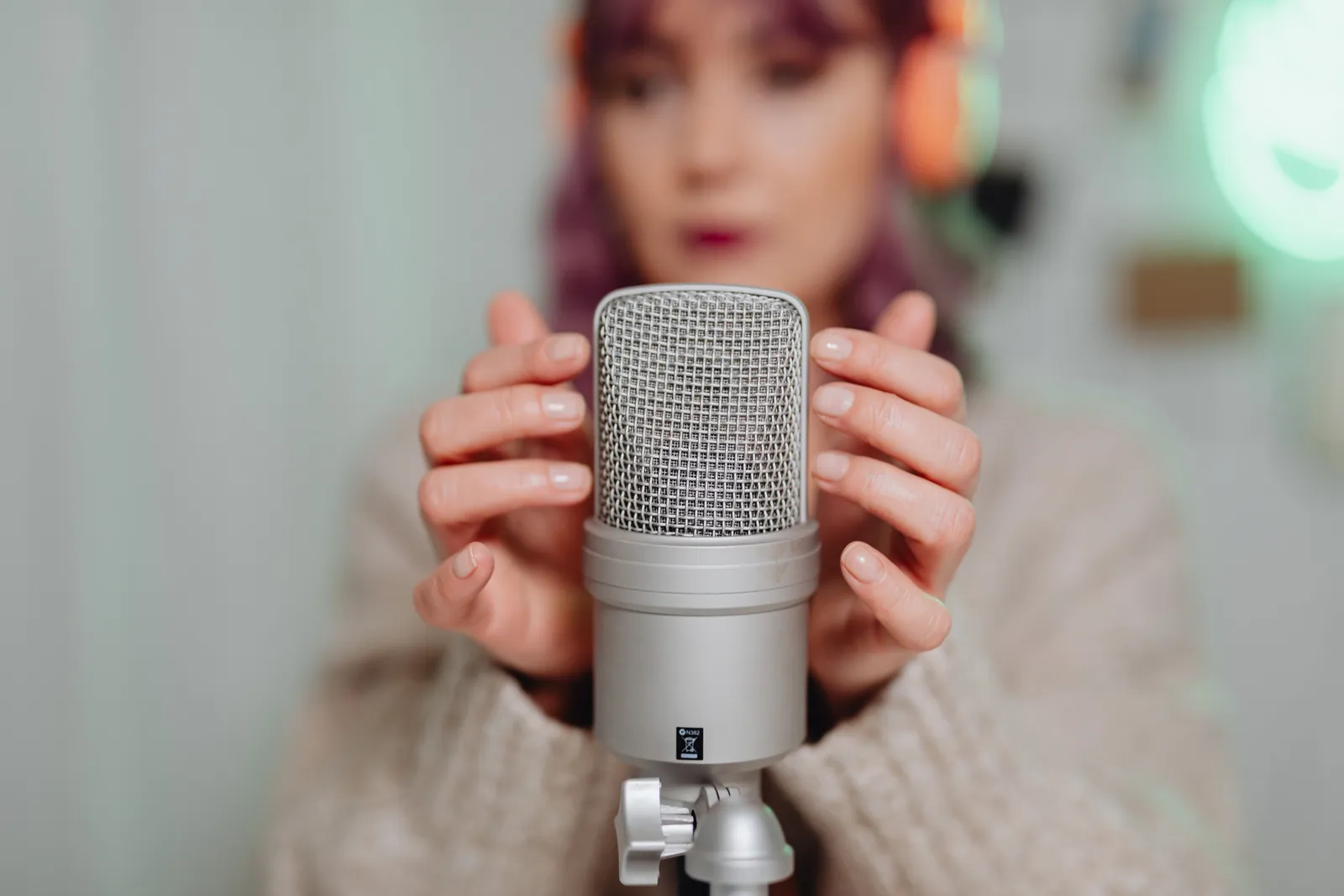 A woman in headphones uses a studio microphone for ASMR recording indoors