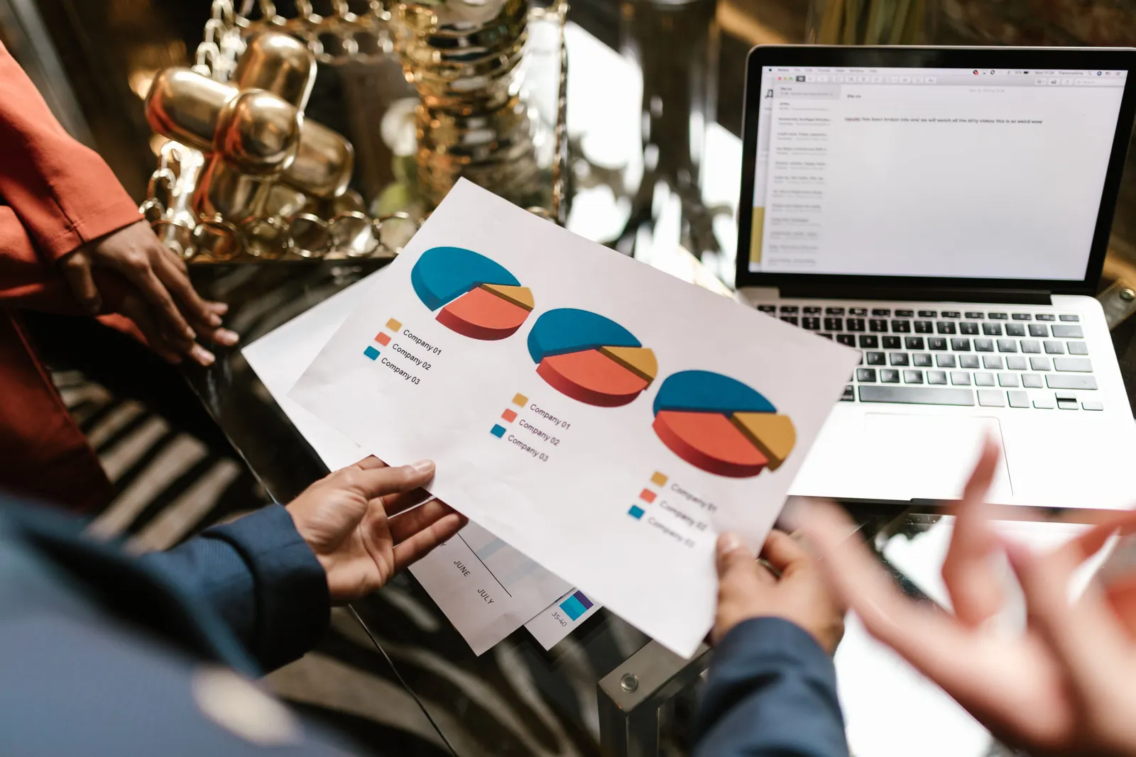 Professional hands holding pie chart data near laptop in modern office setting
