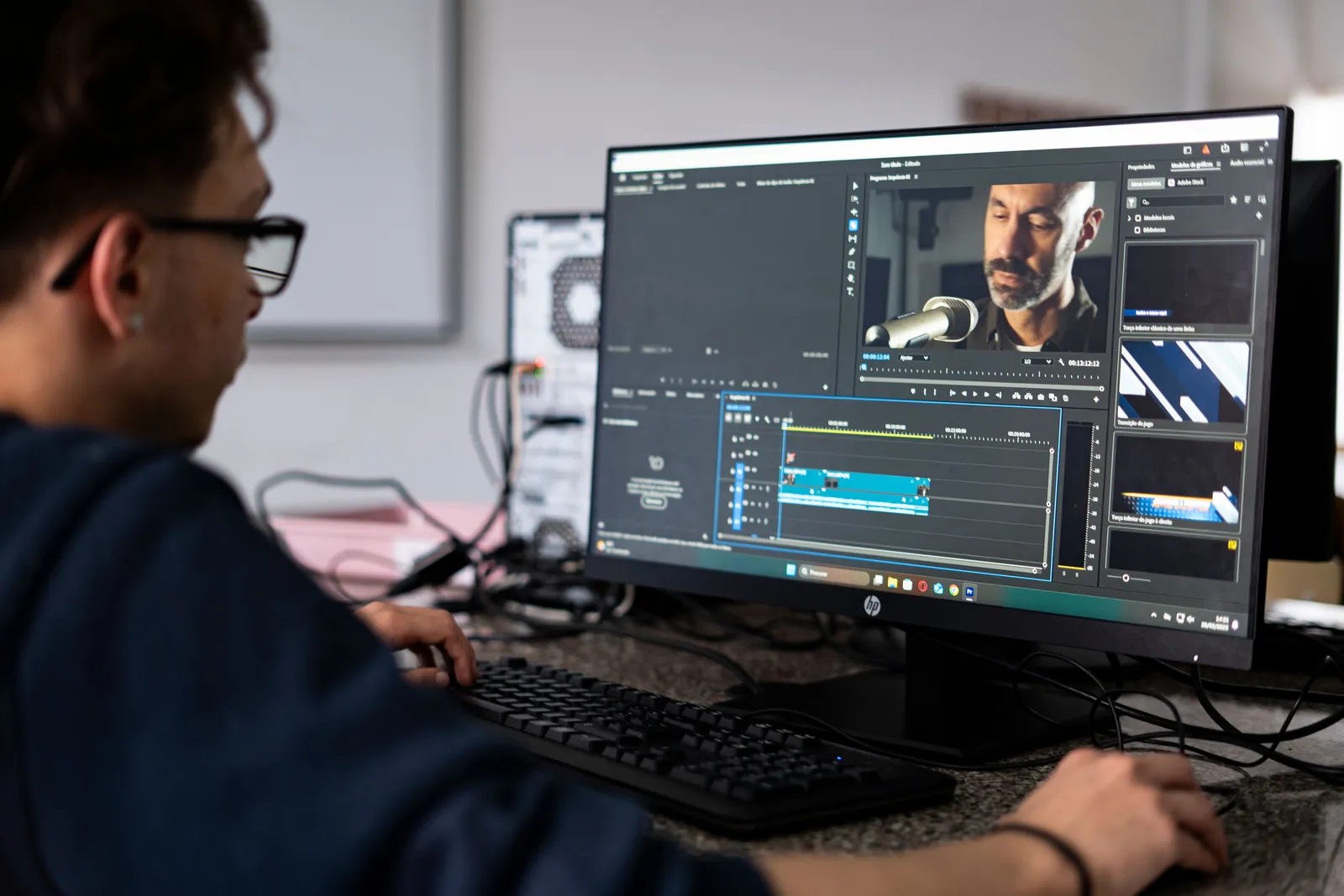 A video editor working on a project using a desktop computer in a modern office setting
